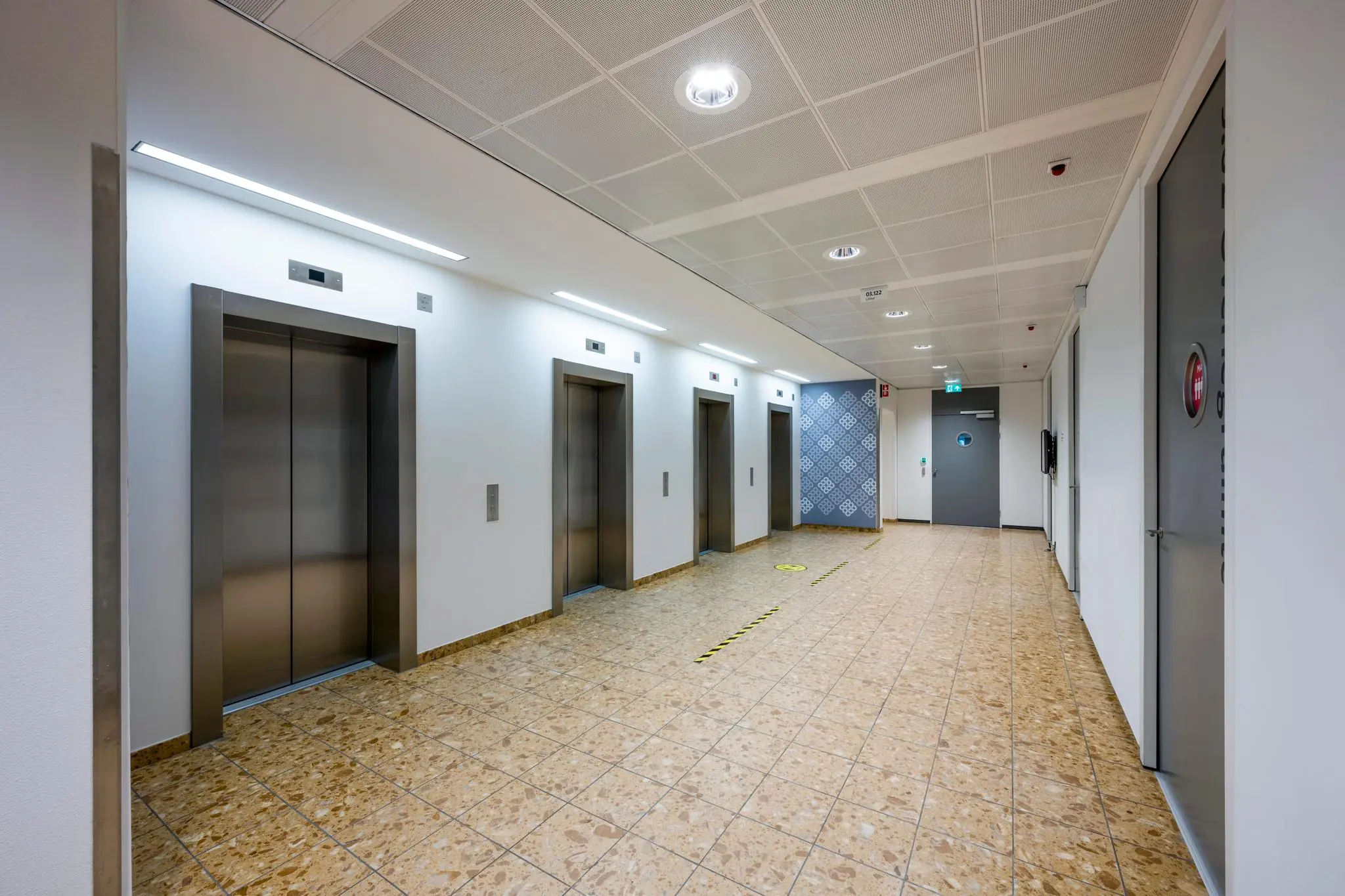 Hal met vier gesloten liften in een modern kantoorgebouw aan de Burgemeester Rijnderslaan.